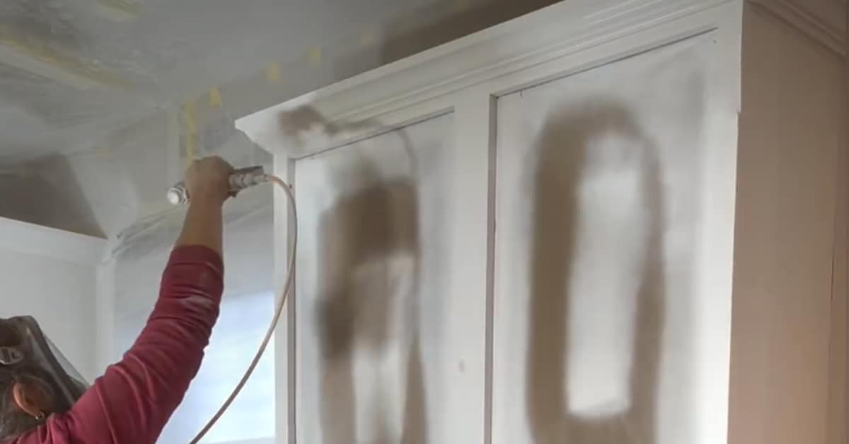 person using airless spray gun to paint kitchen cabinets